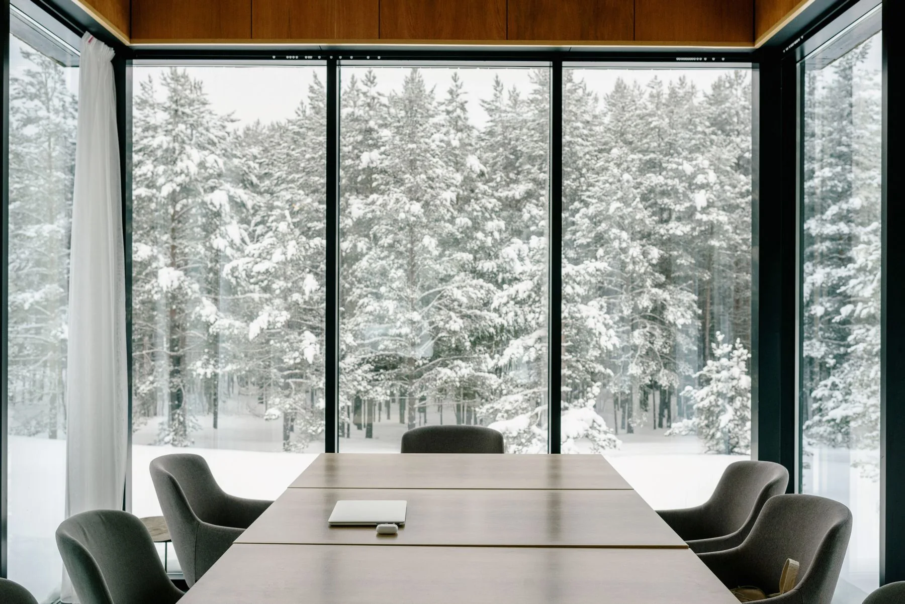 A contemporary meeting room with a long table and views through full-height windows